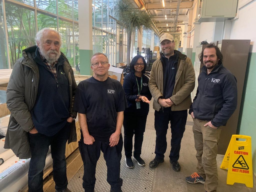 Five people standing in a greenhouse at Kew Gardens, smiling at the camera.