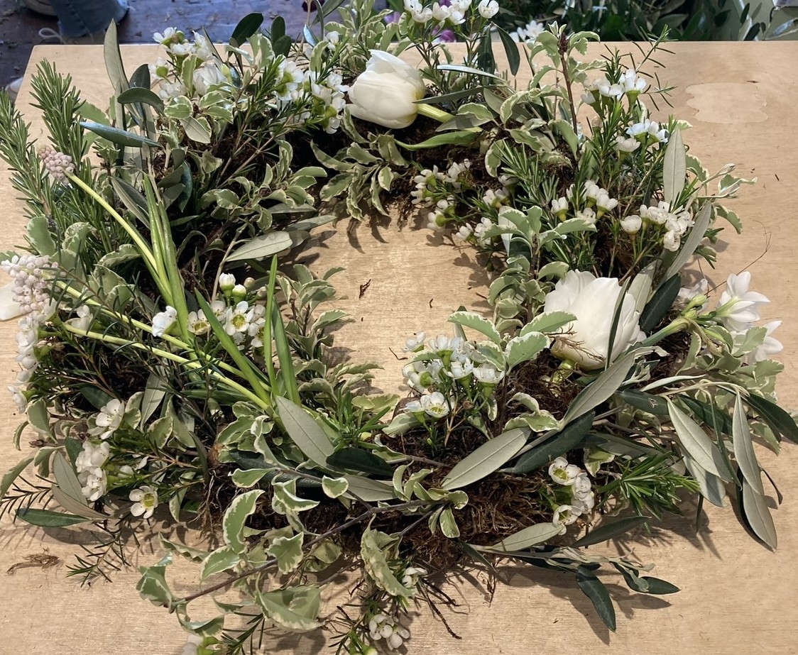 A glasshouse with tall stemmed flowers, known to attract bees, in a border at the front. 