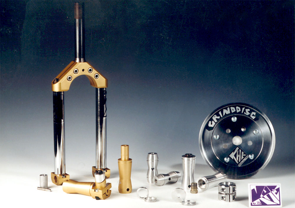 Die Produktpalette von KHEbikes aus den Jahren 1990-91: Links am Bildrand haben wir die Schlachtschiffgabel, die keinerlei Schweißnähte hatte. Die Idee dazu war aus der Not geboren, denn damals konnte man nicht einfach so BMX-Teile in Taiwan herstellen lassen, von Deutschland ganz zu schweigen. In der Mitte gibt es das erweiterte Pegsortiment von KHEbikes und rechts im Bild haben wir die erste doppelstöckige BMX-Sattelklemme ever, die verhindern sollte, das Rahmen am Sattelrohr brechen, was sie damals oft taten, sowie die Grinddisc, die Thomas Göring gemeinsam mit der deutschen BMX-Legende Albert Retey entwickelte und die in leicht abgewandelter Form heute noch als Sprocket Guard von vielen anderen Firmen erhältlich ist