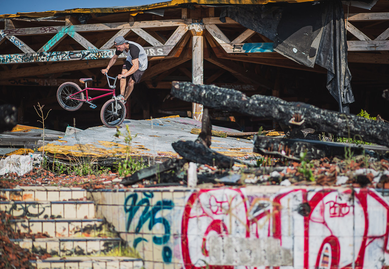 2018 – Markus „Maggi“ Lange – Berlin: Die Wege von Maggi und mir kreuzten sich auf einem kleinen Jam in Berlin und nach kurzem Socialmedia-hin-und-her-Geschreibe verabredete man sich im ehemaligen Spaßbad „ Blubb“ in Neukölln. Diese Ruine existiert schon seit knapp einem Jahrzehnt. Ich kann mich daran erinnern, dass ich dort mal vor Jahren mit Christian Ramin Fotos gemacht hab und dachte, dass der Spot noch halbwegs fahrbar war … Denkste! Die Hütte wurde x-mal angezündet, ist in sich zusammengestürzt und durch Vandalismus mehr als nur „verwüstet“. Wie Maggi da trotzdem noch Tricks ballern konnte, ist mir bis heute ein Rätsel, denn selbst der Weg über das Gelände war schon ein reines Survival-Abenteuer … Aber das Foto ist der Beweis: Radkontrolle at its best!