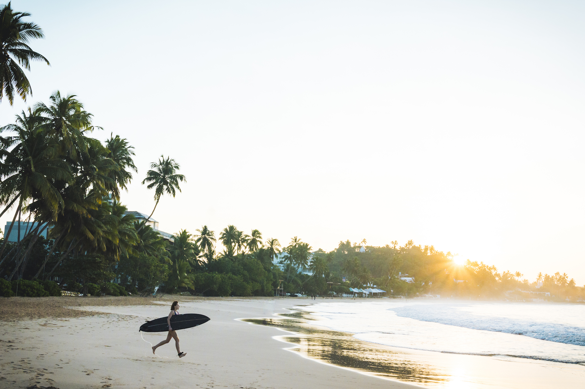 Female surfer runs toward water
