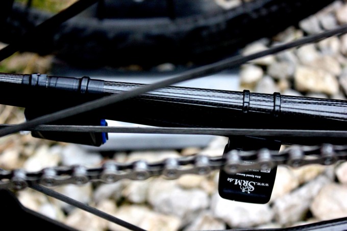 An der linken Kettenstrebe ist Platz genug für Transponder. Hier sieht man auf der linken Seite den Renntransponder von ASO und UCI, der das Signal für die Durchgangs- und Endzeit sendet. Rechts sehen wir einen Transponder für die Geschwindigkeitsmessung des SRM PC7.