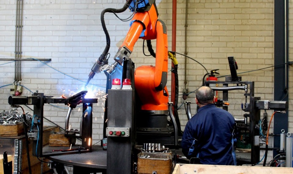 Beim Schweißen der Stahlrahmen für die Heimtrainer arbeiten Mensch und Maschine zusammen.