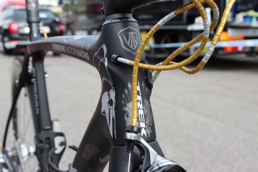 Cancellaras Kabel laufen durch ein Kabelsystem von Nokon. An seinem Aufwärm-Bike in Gold und später an der Rennmaschine in Rot. Man beachte auch die 7 Speere am Steuerrohr.