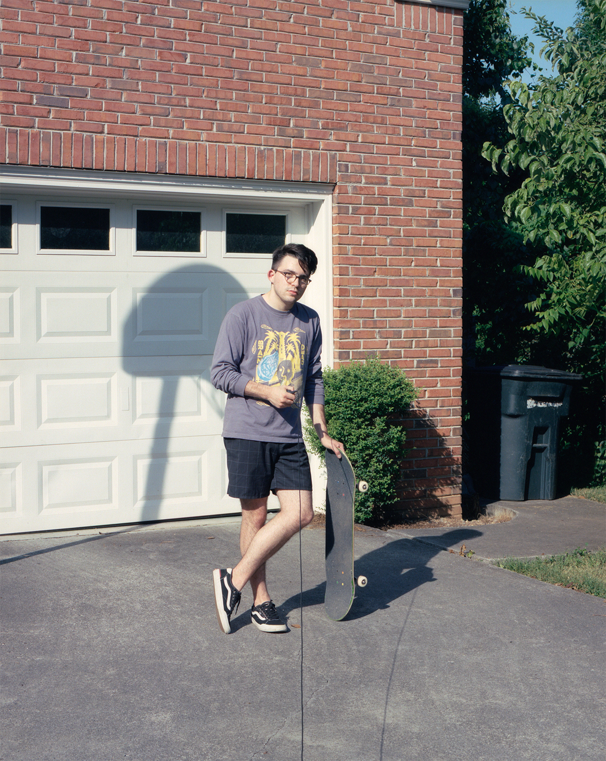 Selbstporträt von Ross wie er mit einem Skateboard vor einer Garage posiert