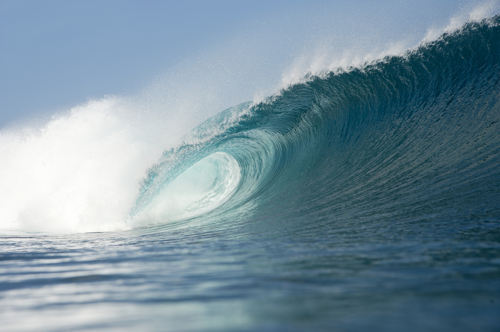 How are Waves Formed?  a beautiful blue wave breaking over shallow coral reef in Indonesia