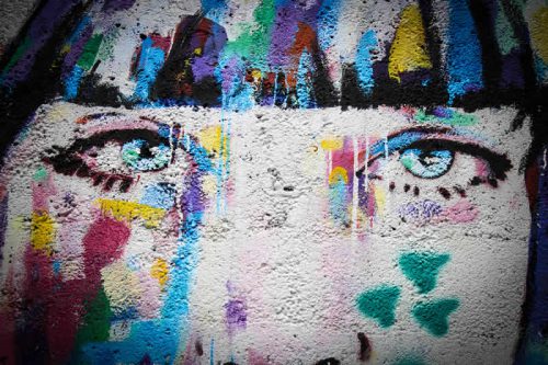 Ein buntes Graffiti, das das Gesicht einer jungen Frau zeigt.