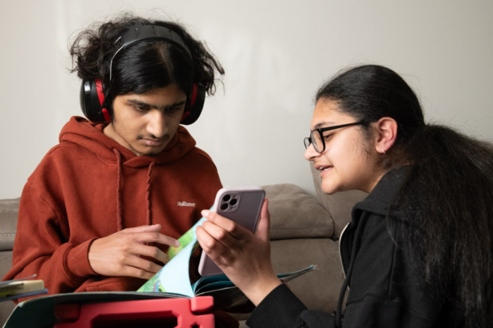 A sister shows something on her phone to her brother