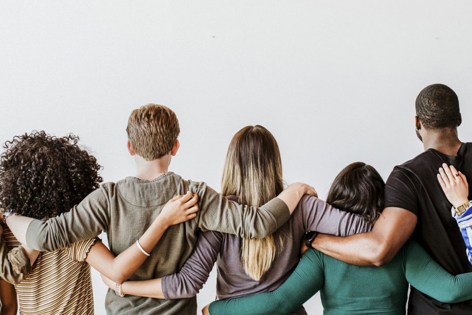 A chain of people facing away from the camera with their arms around each other