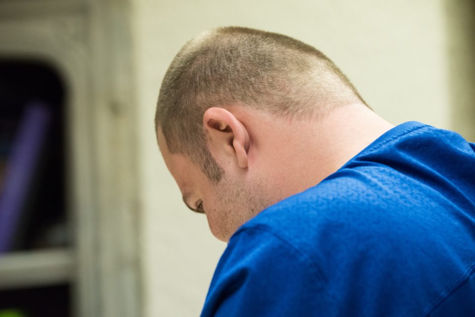 Adult looking down, with his back to the camera.