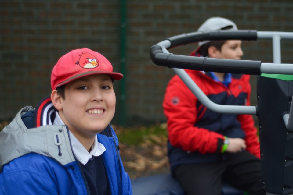 Two children sitting in a playground and smiling