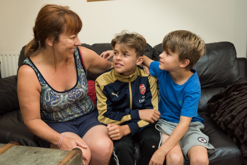 Mother with two boys hugging on the sofa.