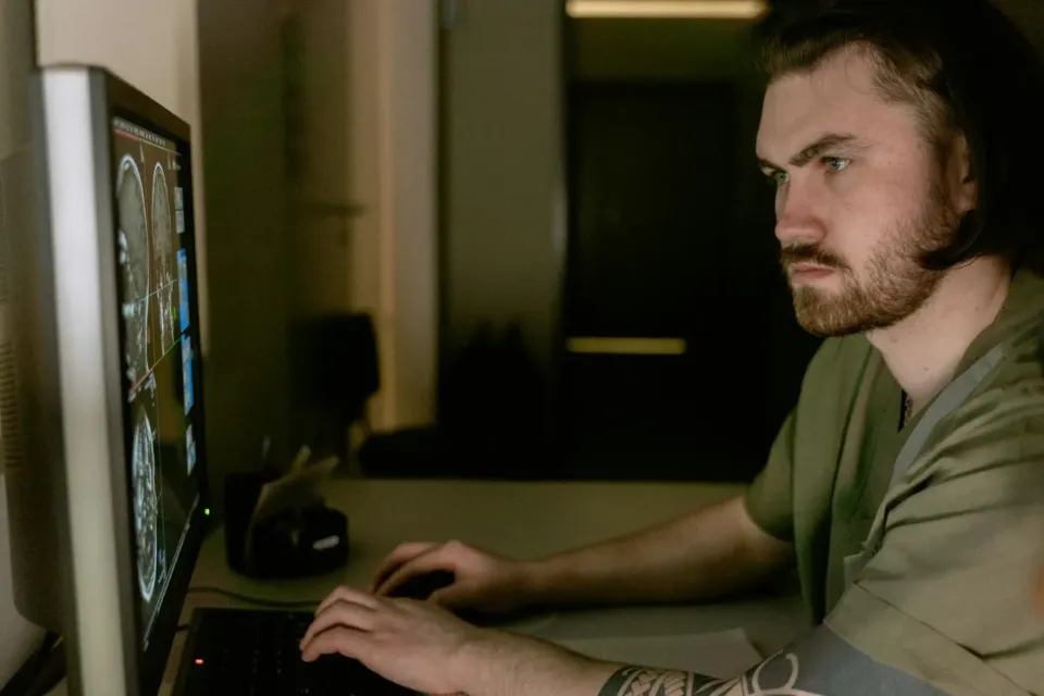 A clincian looking at a brain scan on the computer - Image credit: Mart Production via Pexels