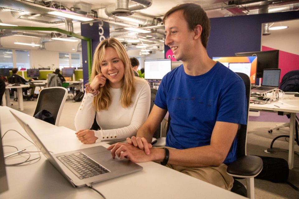 Two smiling people looking at a laptop