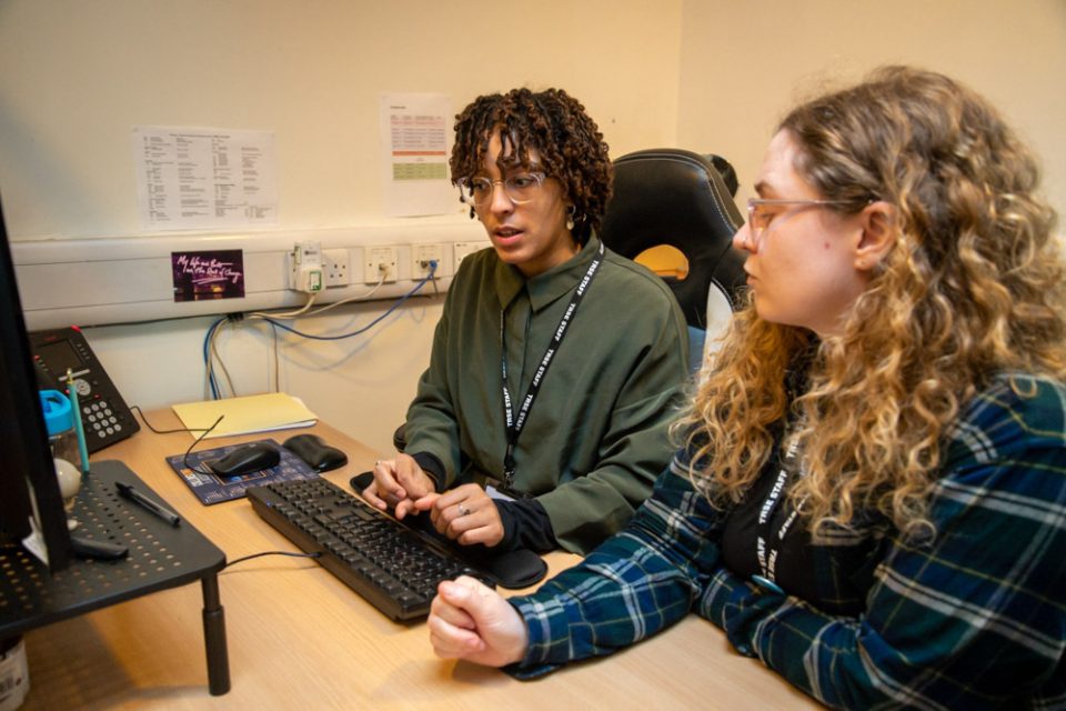 Two employees work at a computer together