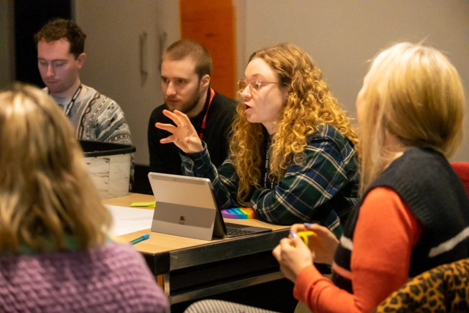 Our neurodiversity training and consultancy team: a photo of a team meeting with someone talking animatedly.