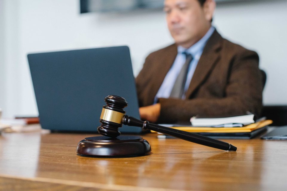 A gavel, and a man on his laptop in the background