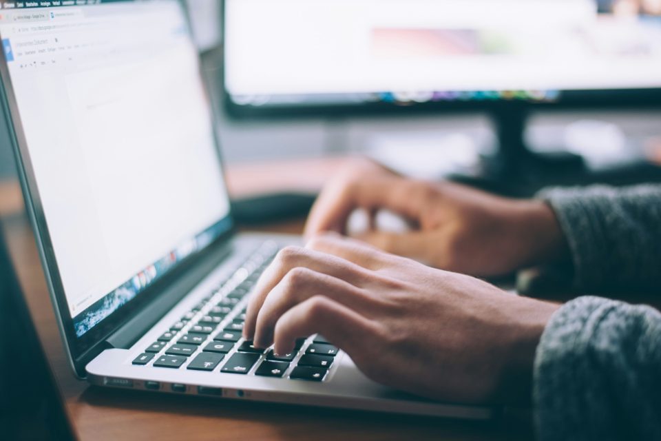 Hands typing at a laptop.