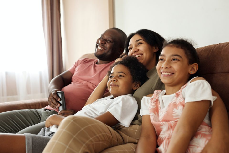 A family cuddling on the sofa smiling