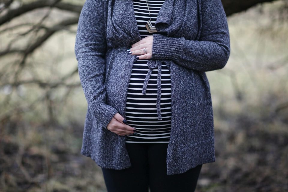 An image of a pregnant woman cradling her stomach