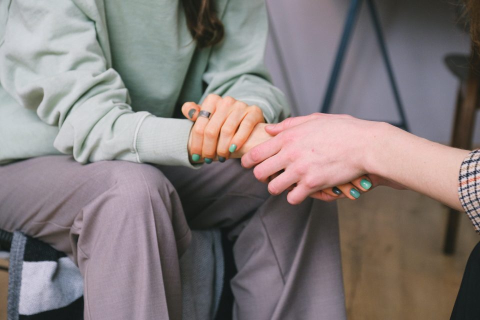 Two people facing each other, touching hands. Close up on their hands.