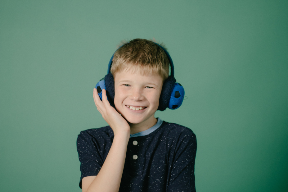 A young smiling boy wearing ear defenders