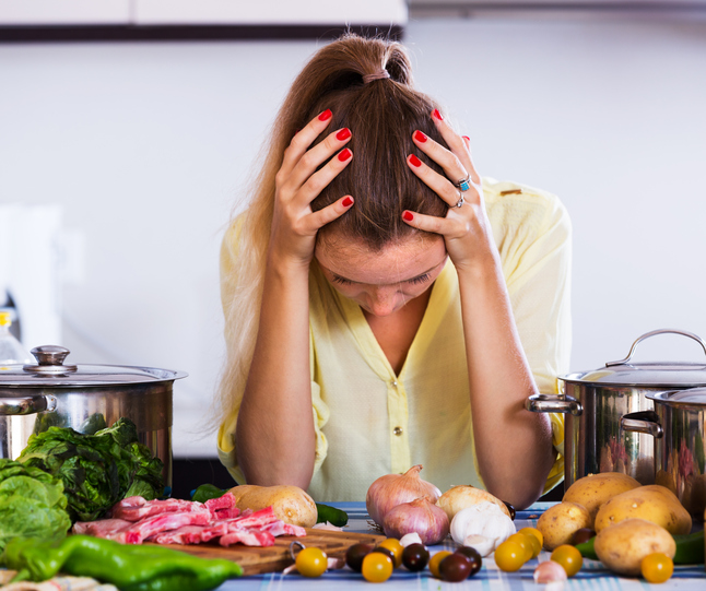 Fatigued housewife with meat and vegetables at kitchen table