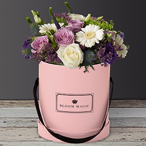 S'aimer sur le Pont Neuf is a wonderful arrangement of flowers delivered in a blush pink hatbox. The S'aimer sur le Pont Neuf features white avalanche roses, purple lisianthus, and white mini-gerbera. The  S'aimer sur le Pont Neuf would make a perfect arrangement of flowers for the arrival of a new baby boy or as birthday flowers. Whatever the occasion these flowers would be sure to please!