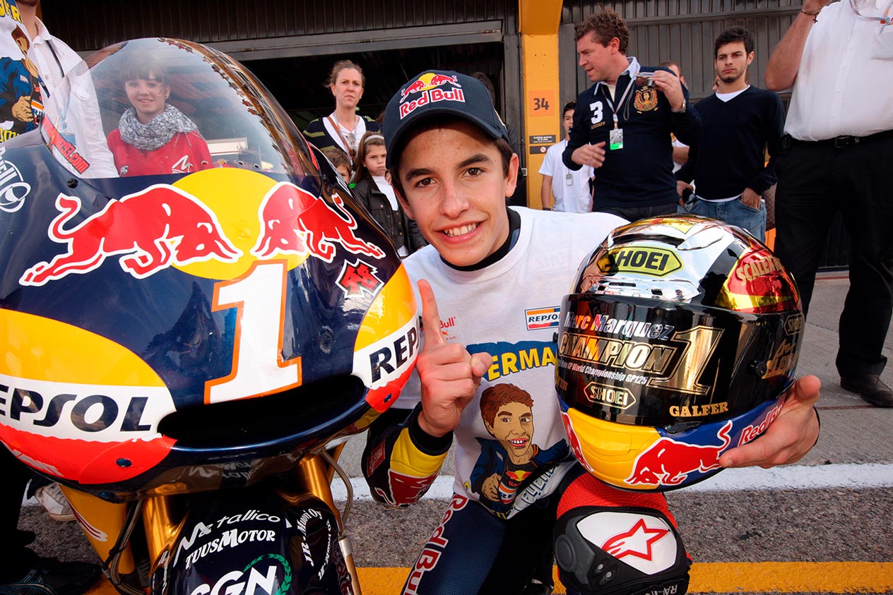 Marc Márquez señala el 1 de campeón en su moto de 125cc. Marc Márquez junto a su moto con un 1