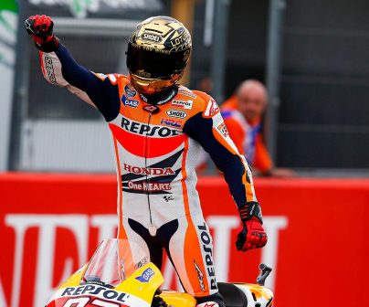 Marc Márquez con casco dorado levantado sobre la moto