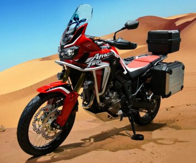 Una Honda Africa Twin de lado con dunas dunas de fondo en el desierto