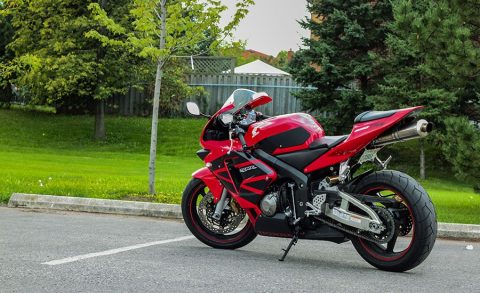 Honda CBR 100 RR Fireblade aparcada en la calle frente a un parque. Una Honda CBR 1000RR Fireblade roja y negra aparcada en la calle frente a un parque