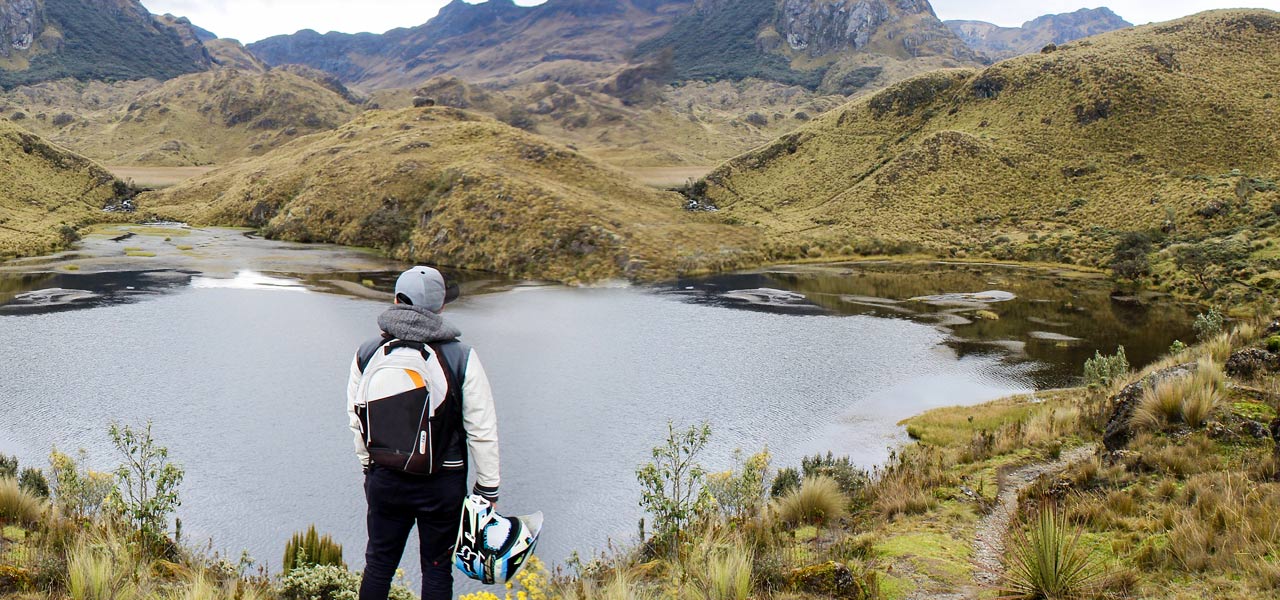Motero observa las montañas del norte de España en su ruta motera Motero mira las mágnificas vistas naturales de un lago