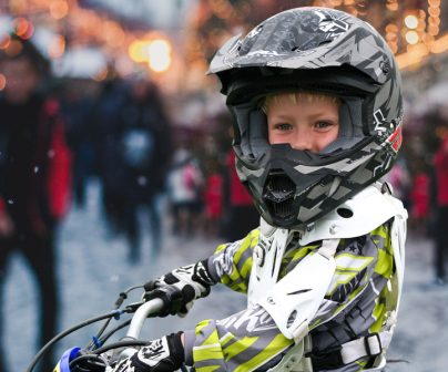 Niño con casco y mono de motocross en un ambiente navideño