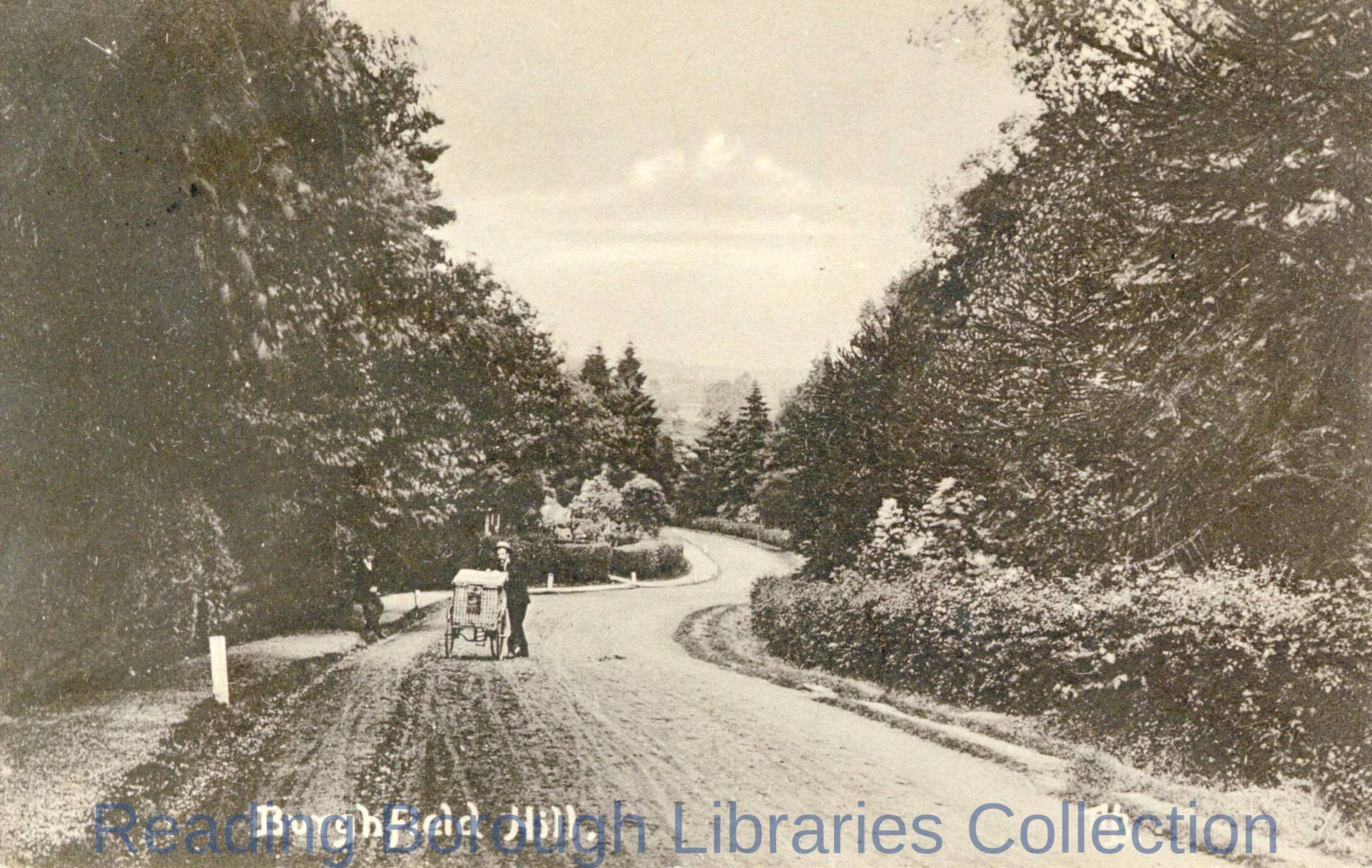 A man pushing a handcart, which carries a large wicker hamper up the hill towards the camera, Burghfield Hill, c1910 A man pushing a handcart, which carries a large wicker hamper up the hill towards the camera, Burghfield Hill, c1910