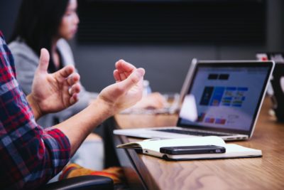 Man hand gesturing in front of laptop