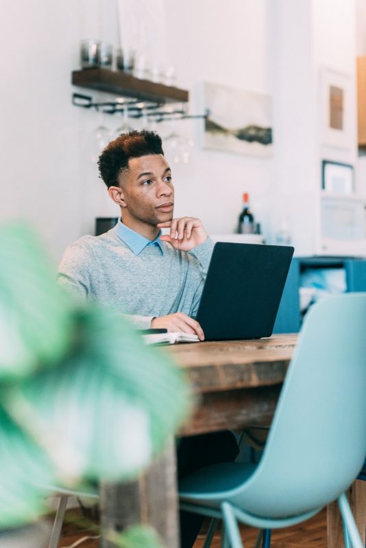 Man at laptop in cafe thinking