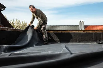 A man fitting rubber roofing to a roof which will last up to 30 years.