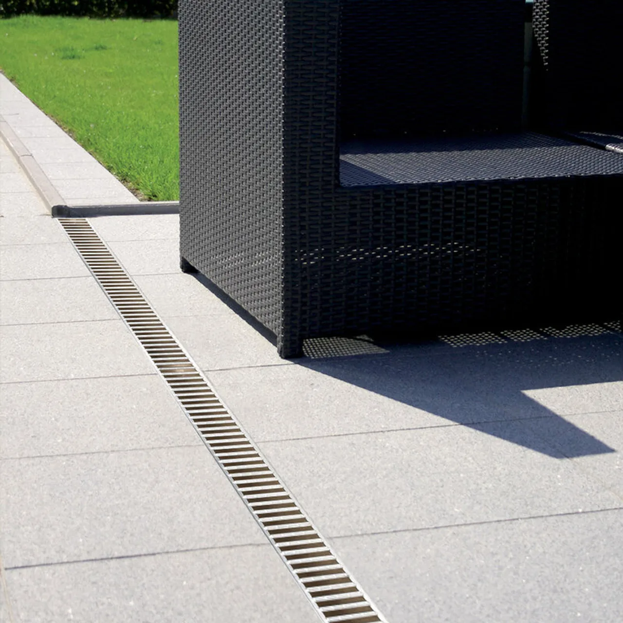 A close-up picture of some drainage grills next to an outdoor furniture seat.