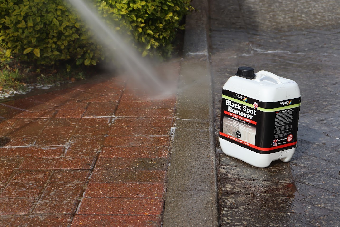 An image of someone using a jet wash to clean the block paving beneath them. 