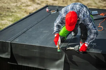 A man attaching felt to the side of a shed to weatherproof it. A man attaching felt to the side of a shed to weatherproof it.