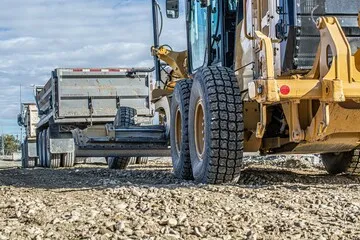 A tractor being used over a bed of gravel, showing that it is a construction project.