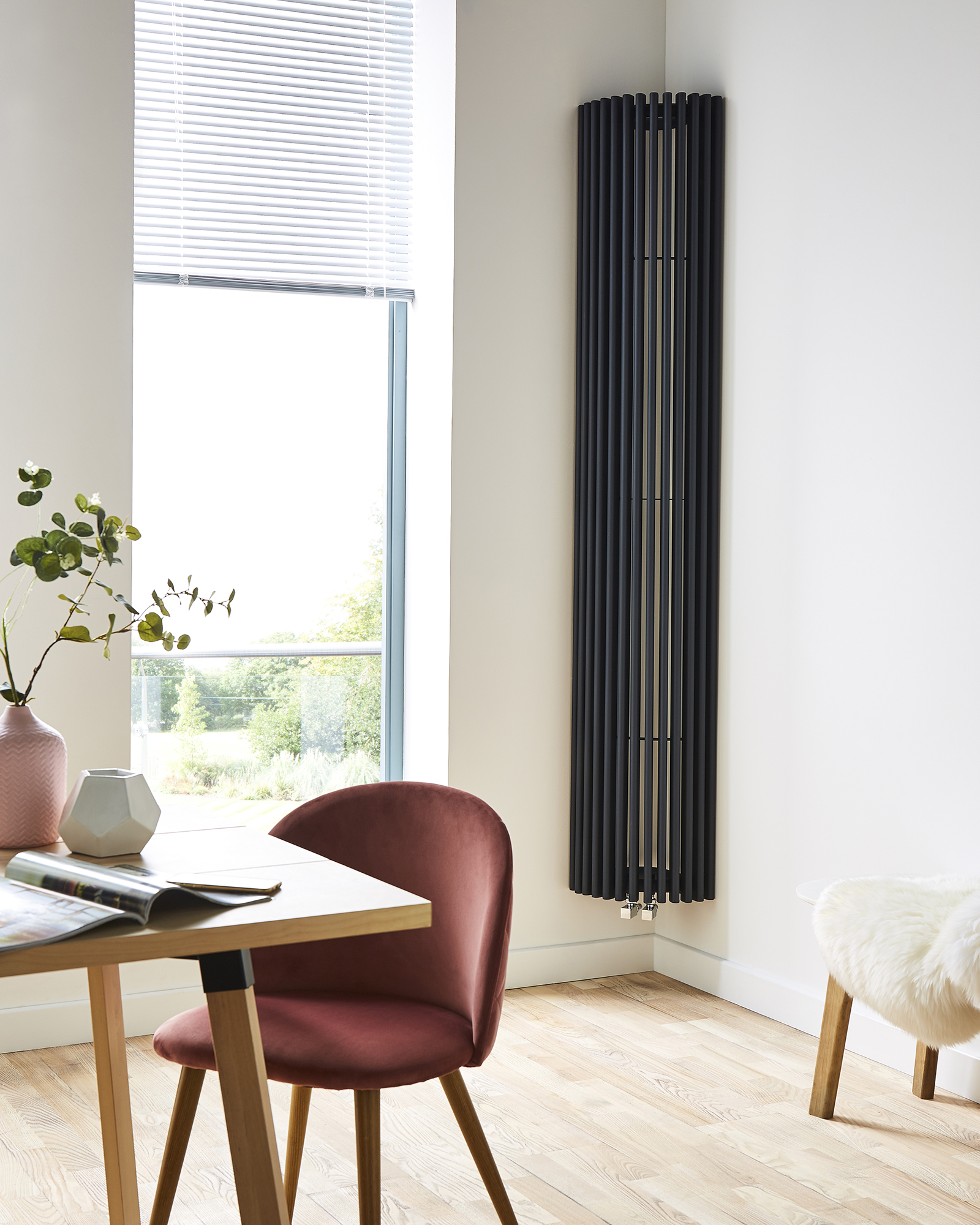 A black decorative radiator across the height of a white wall. 