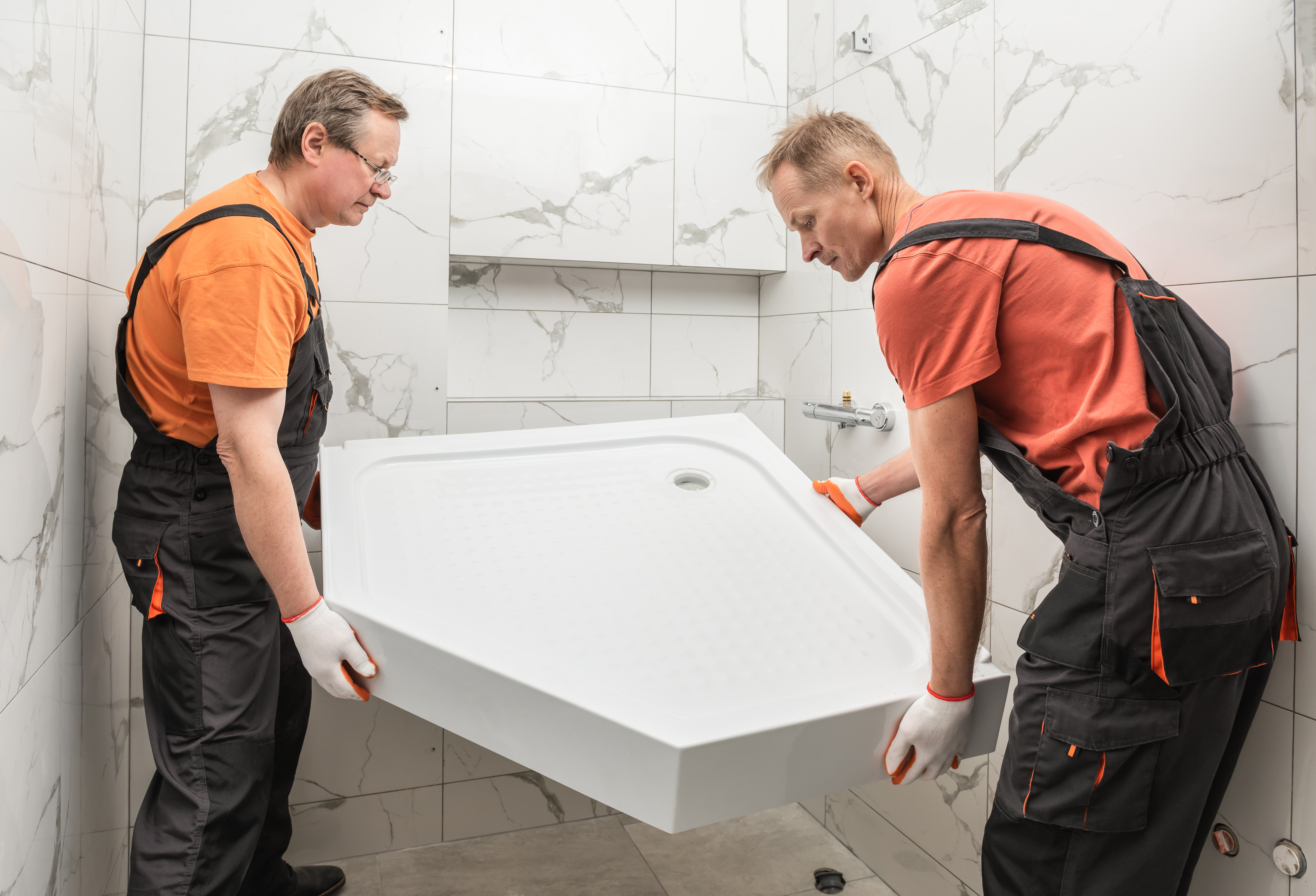Two installers fitting a shower tray.