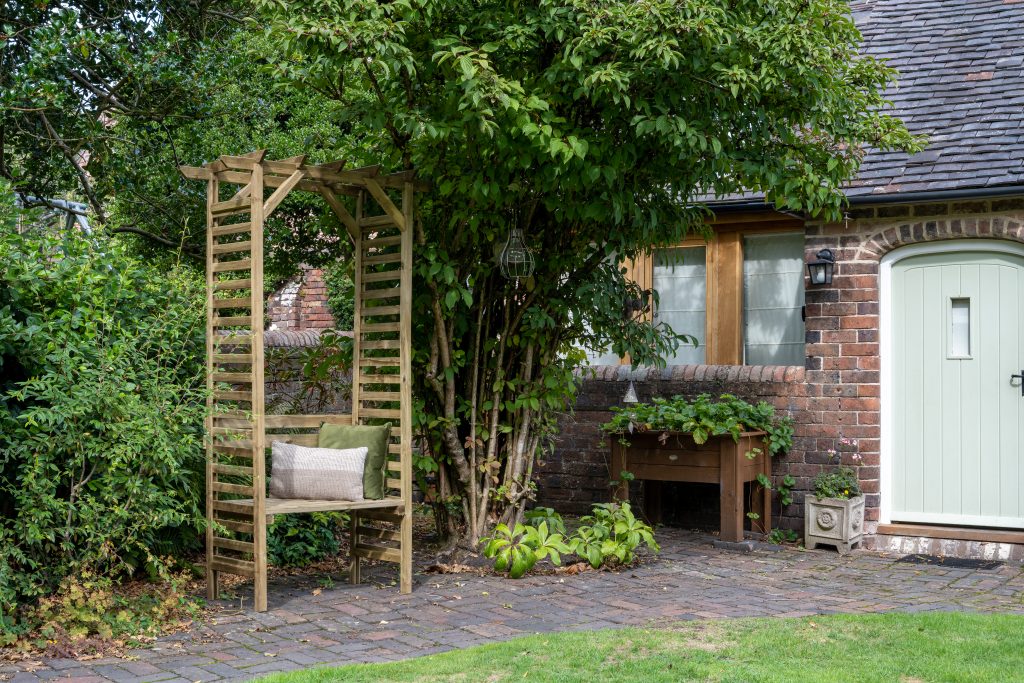 A garden bench situated in the middle of a garden path in a garden to create a homely, cosy space. 