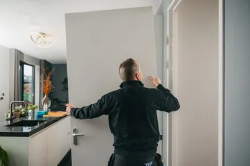 Door installation in a home, with a man attaching a door to the hinges.