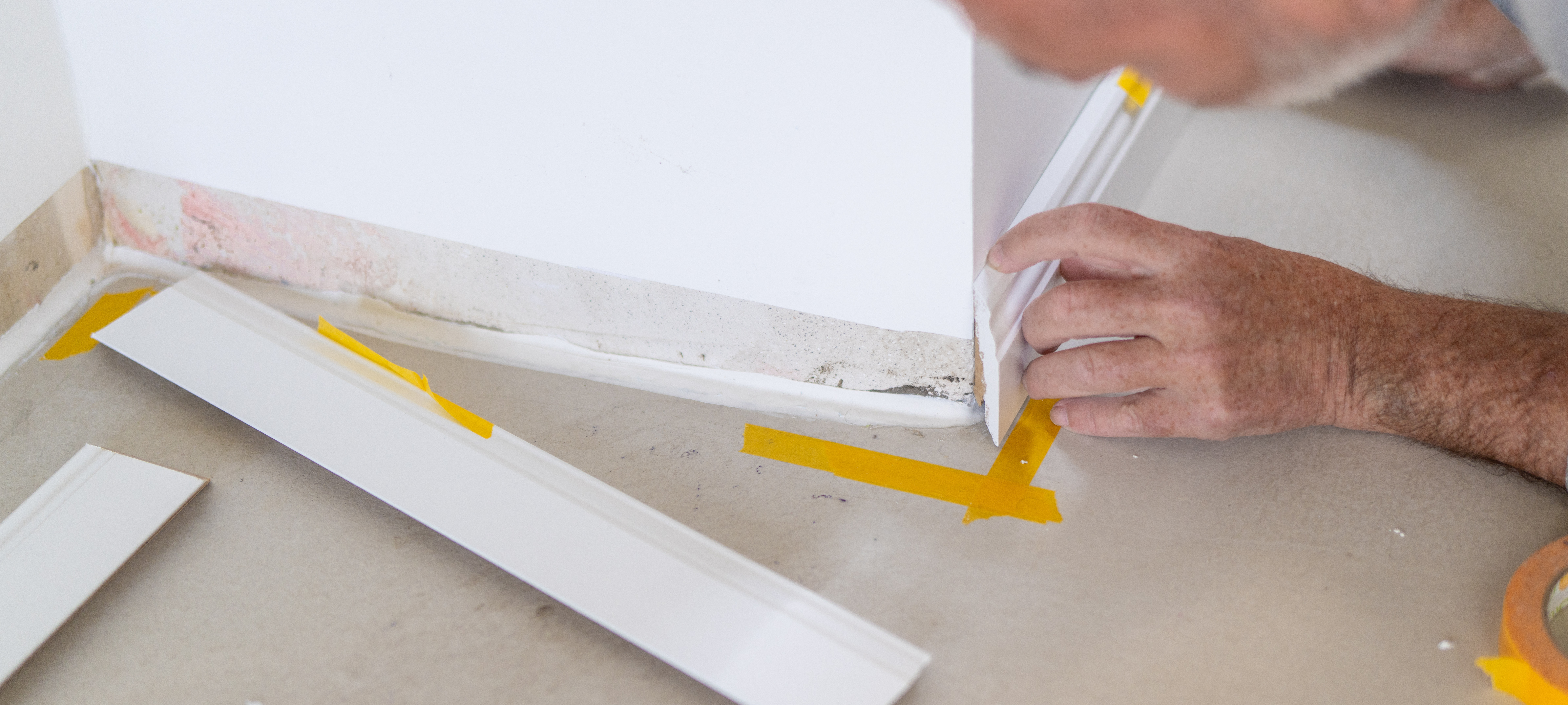 an image of a man applying adhesive to skirting board