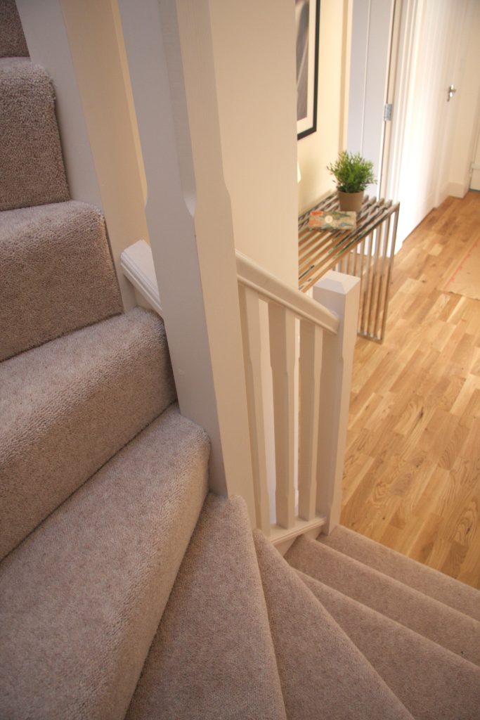 A landing of a house with stairs being used to spiral around the room space and up towards the loft conversion. 