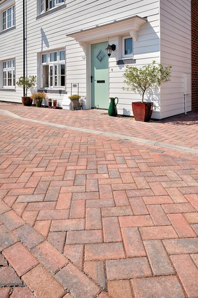 an image of a man applying kiln-dried sand across the block paving