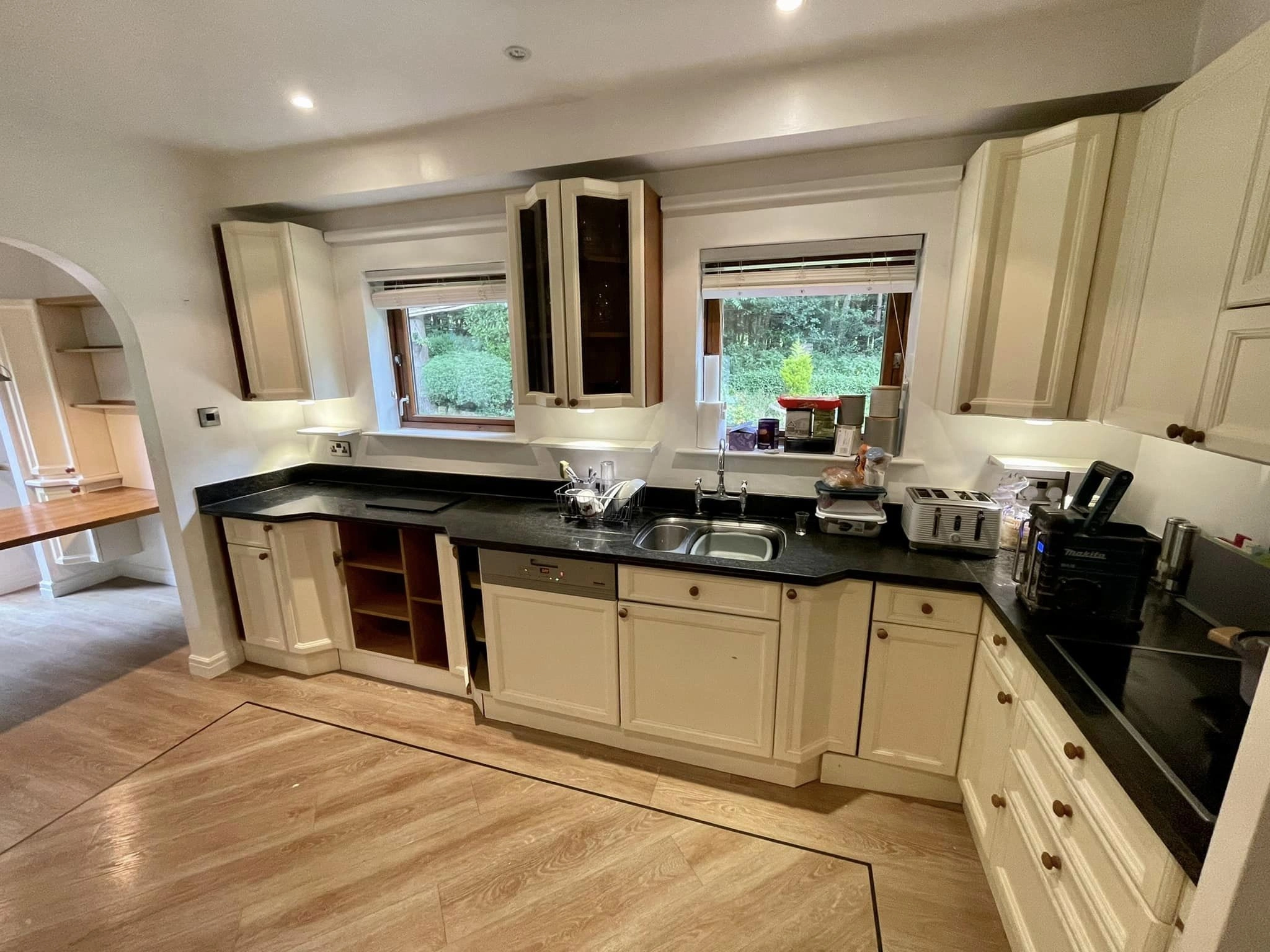 A traditional looking bathroom with white cabinets, black worktops and wooden details.